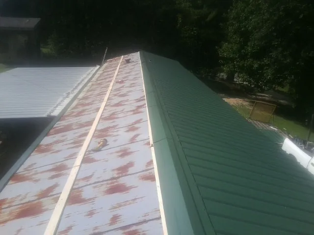 Old rusted panels beside newly installed green metal roofing — Wind Damage Roof Repair by Roofing Brothers in Bolinas