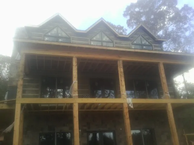 Dormers and porch framing on a large log home under construction — Roof Coating work by our crew in Bolinas