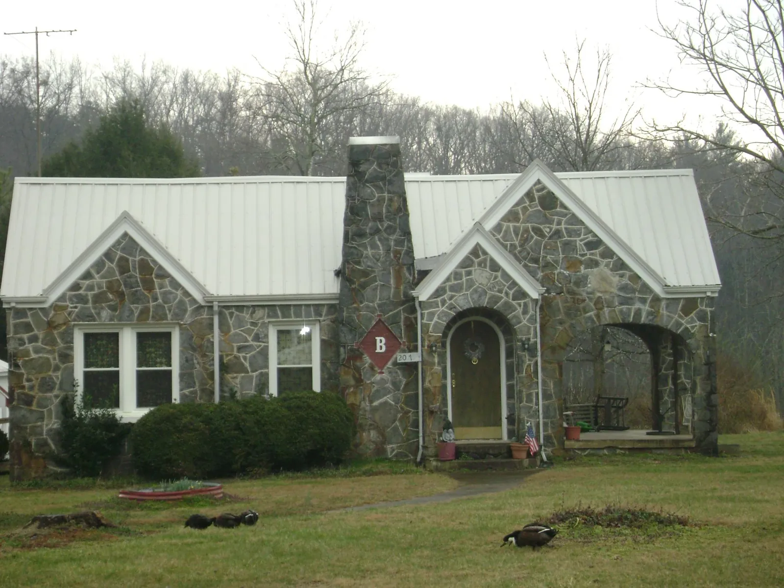 White metal roof on a stone cottage with steep gables in Bolinas