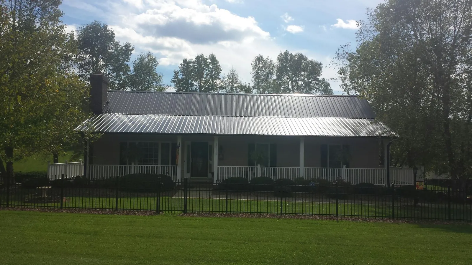 Gray metal roof on a brick ranch with a full width front porch — Gutter Guard Installation work by our crew in Bolinas