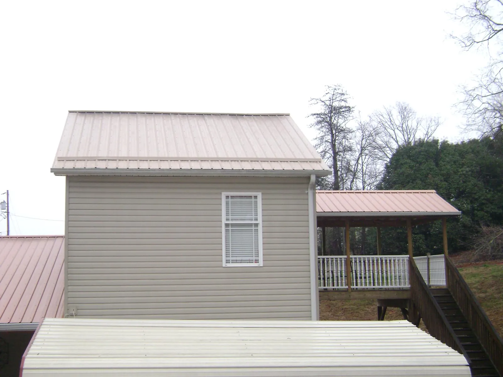 Tan metal roofs on a two story addition and attached porch, from a Roof Replacement job in Bolinas