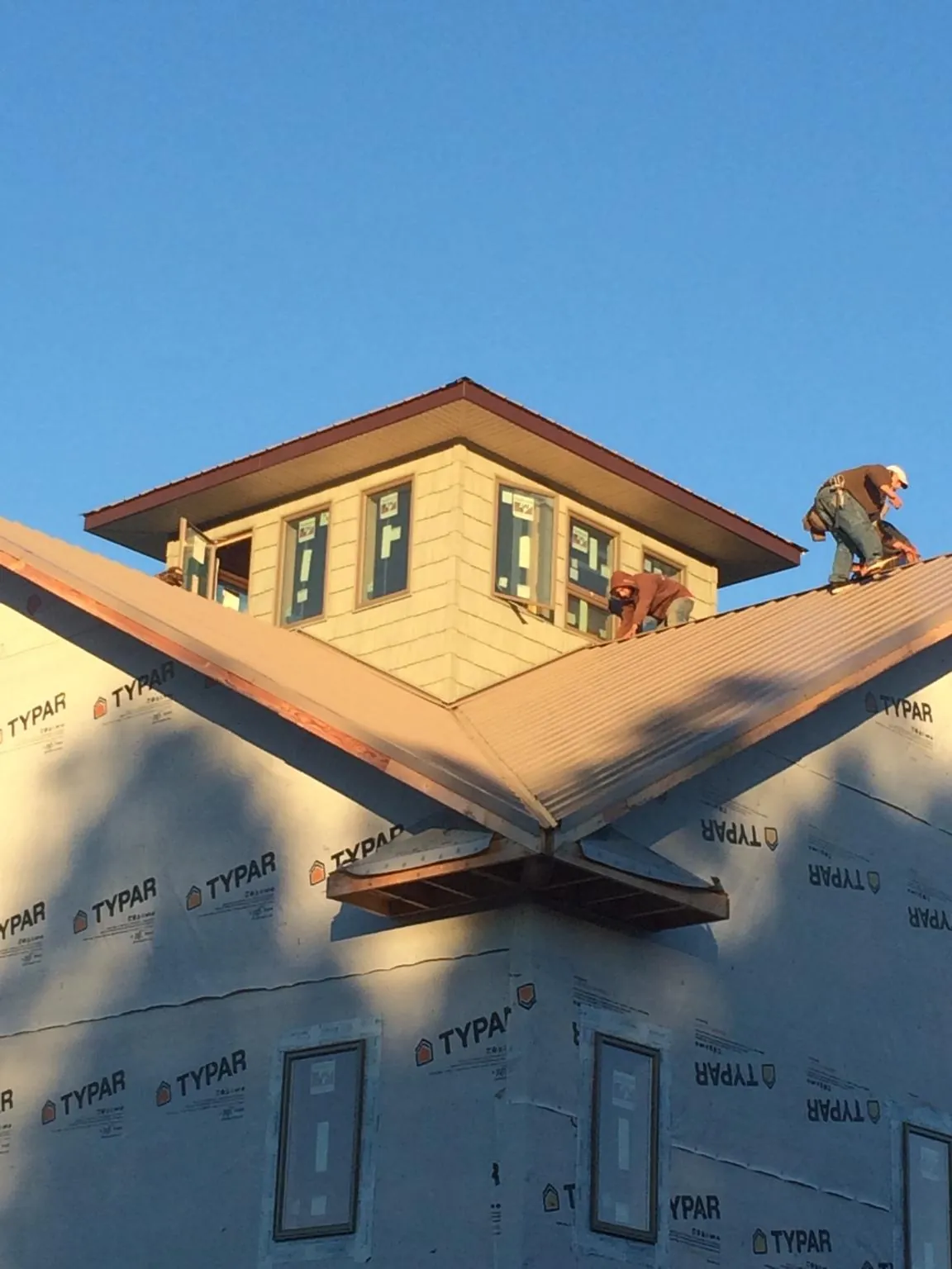 Roofers working around a rooftop cupola on a new metal roof at sunset — Roof Waterproofing in Bolinas by Roofing Brothers